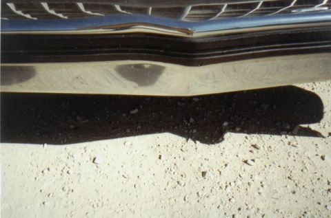 1986 Ford Crown Victoria LTD - A close-up shot focuses on the chrome bumper and grille of a vehicle, with a shadow cast on the ground.