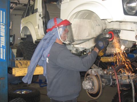 1987 Suzuki Samurai - A person works on the frame of a 1987 Suzuki Samurai with an angle grinder.