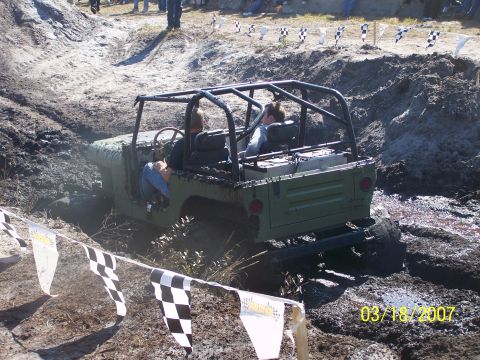 1989 Ford Bronco - An off-road vehicle navigates a muddy track during an event.