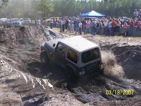 1989 Ford Bronco - Jeep Wrangler tackling a challenging mud pit during an off-road event.