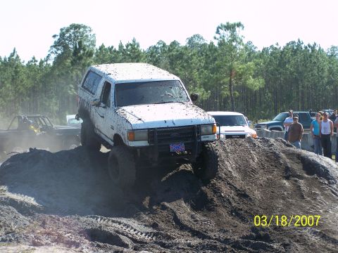 1989 Ford Bronco - A white 1989 Ford Bronco navigates a muddy incline during an off-road event.