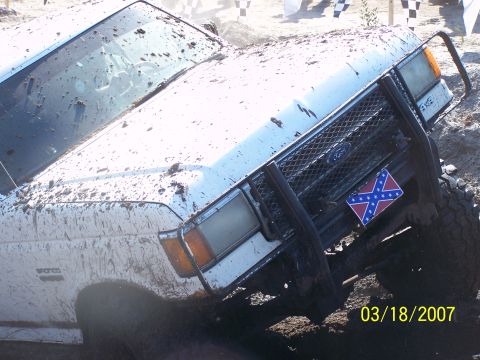 1989 Ford Bronco - Muddy 1989 Ford Bronco with a push bar and Confederate flag, stuck in dirt.
