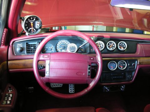 1992 Ford Crown Victoria - The interior of a 1992 Ford Crown Victoria shows a red dashboard with multiple aftermarket gauges and a large tachometer mounted on the A-p…
