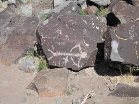 1997 Chevrolet C/K Pickup - Ancient petroglyphs are etched into the surface of large rocks in a dry, outdoor environment.