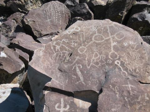 1997 Chevrolet C/K Pickup - Ancient petroglyphs are visible on several large rocks, depicting various symbols and figures in a desert environment.