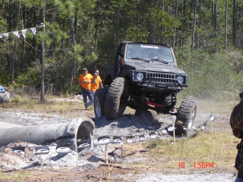 1989 Ford Bronco - An off-road vehicle tackles a challenging course with concrete pipes and dirt mounds.