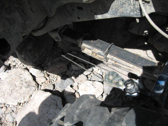 Undercarriage view of a vehicle leaf spring and suspension over rocks