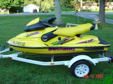 1989 Ford Bronco - Yellow Sea-Doo XP jet ski on a trailer in a grassy yard.