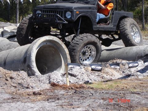 1989 Ford Bronco - A modified off-road vehicle tackles a challenging course with large concrete pipes as obstacles.
