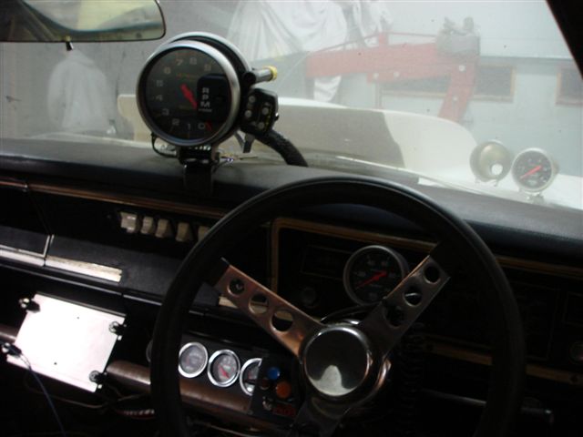 1968 Ford Mustang interior with a large tachometer, aftermarket gauges, and a custom steering wheel
