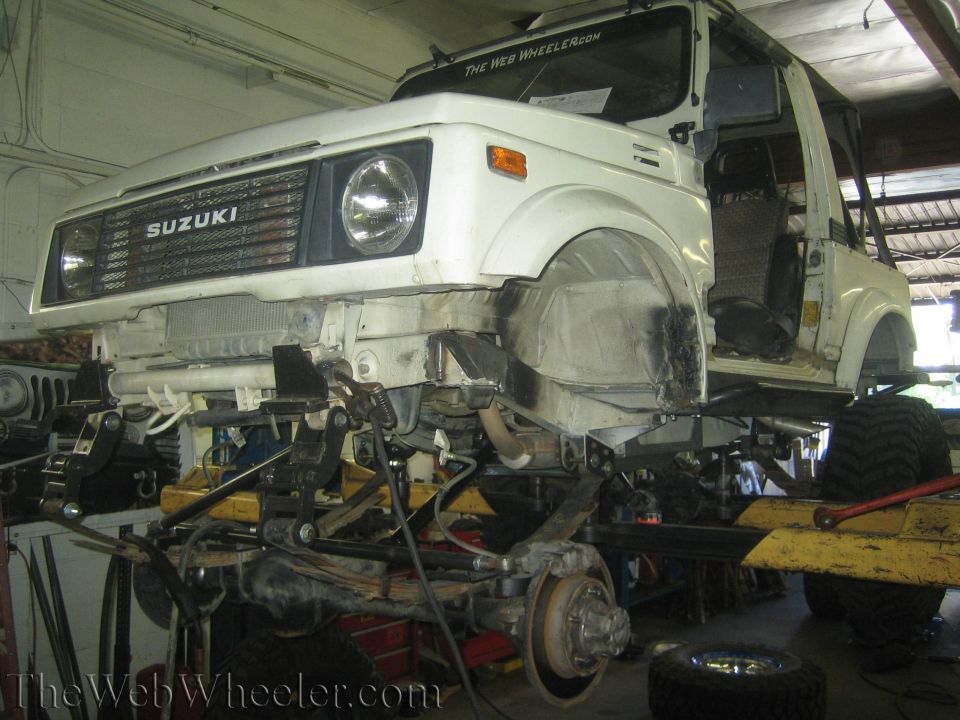 White 1987 Suzuki Samurai front end disassembled, showing suspension and frame modifications