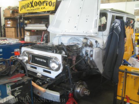 1987 Suzuki Samurai - Front end of a Toyota Land Cruiser FJ40 undergoing repairs in a workshop.