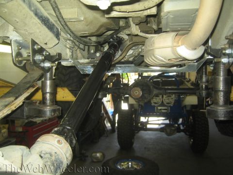 1987 Suzuki Samurai - Close-up of vehicle undercarriage, focusing on drivetrain and suspension parts during modification.