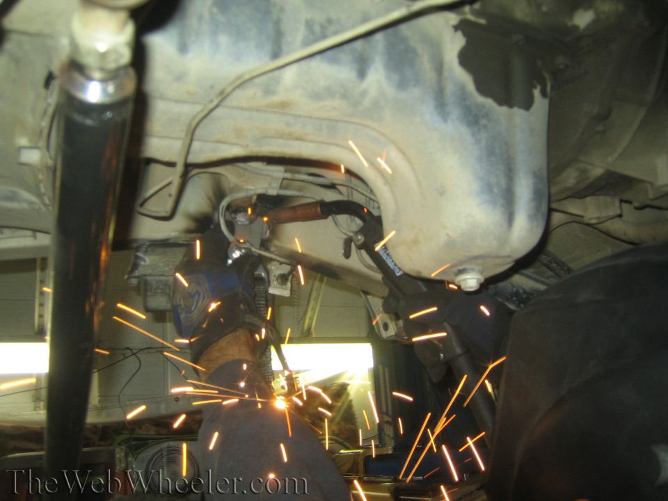 Welding sparks fly from undercarriage of vehicle during shock swap