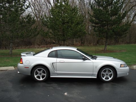 1998 Ford Taurus - Side profile of a silver Ford Mustang coupe with a spoiler.