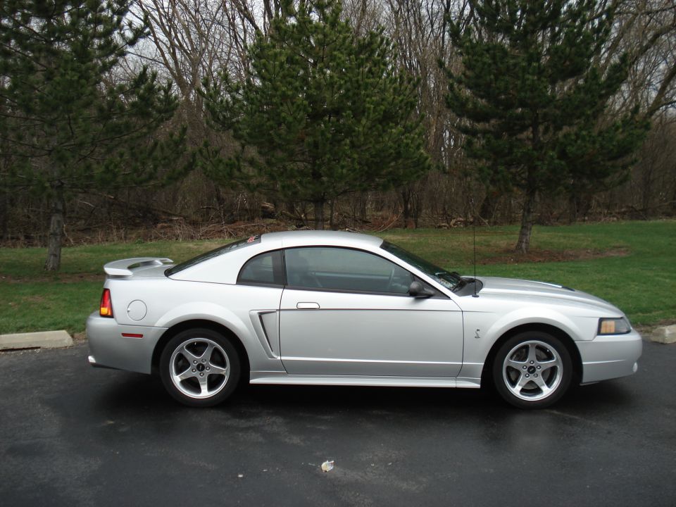 Silver Ford Mustang parked on asphalt, side view