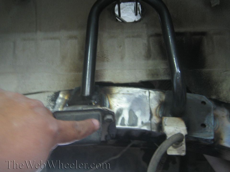 Close-up of welding on a vehicle's frame with a hand pointing