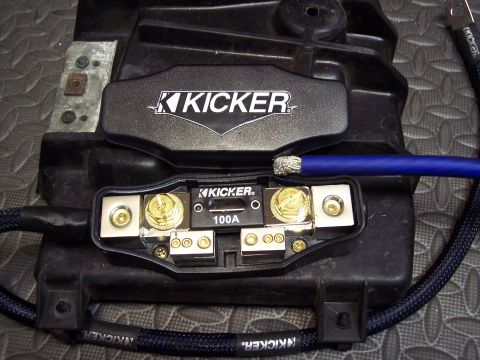 1995 Ford Probe - Close-up of a Kicker audio fuse holder and distribution block, rated for 100A, with a blue power wire connected.