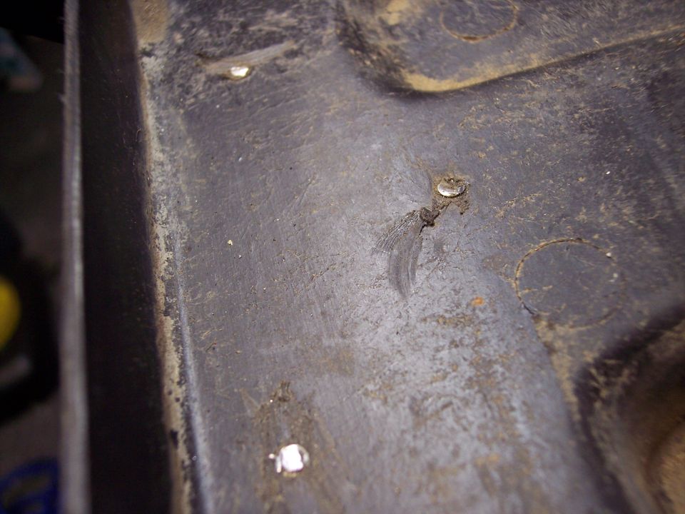 Close-up of a dark, textured interior car panel with visible rivets and some dirt