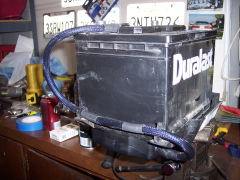 1995 Ford Probe - A car battery with blue braided cables is mounted on a workbench.