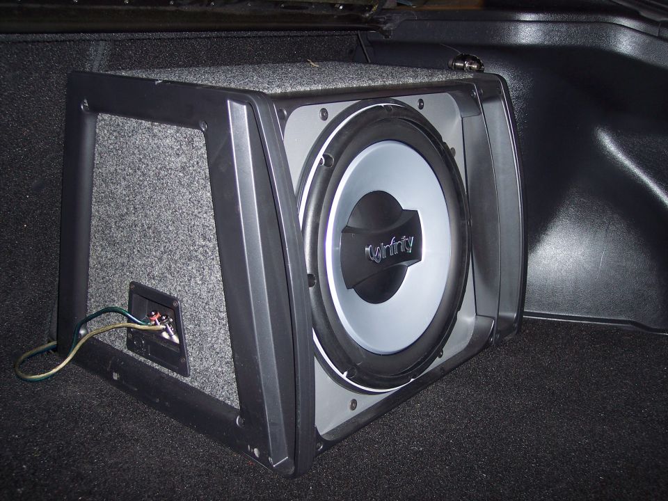 Infinity subwoofer in a carpeted wedge box installed in a car trunk