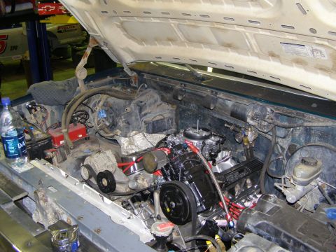 1993 Ford Bronco - The engine bay of a vehicle is shown with various components and a bottle of water on the fender.