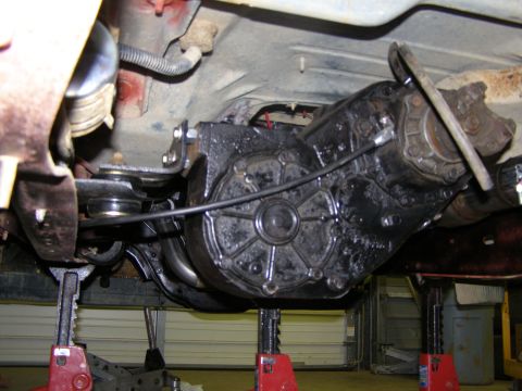 1993 Ford Bronco - Underside view of a vehicle's transfer case and driveshaft, supported by red jack stands.