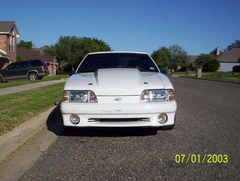 1991 Ford Mustang - A white 1991 Ford Mustang is parked on the street in front of a house.