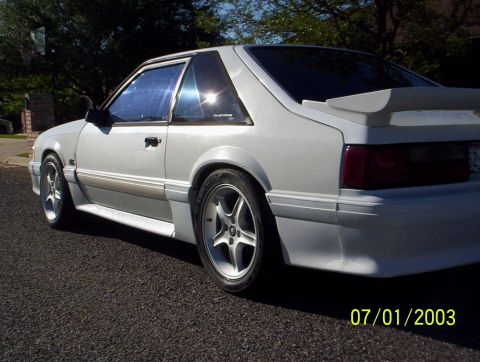 1991 Ford Mustang - A white 1991 Ford Mustang coupe is parked on an asphalt surface, viewed from the front quarter angle.