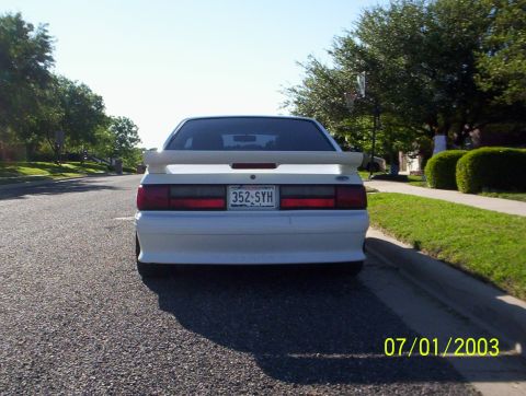 1991 Ford Mustang - Rear view of a white 1991 Ford Mustang, identifiable by its distinct body style and spoiler.