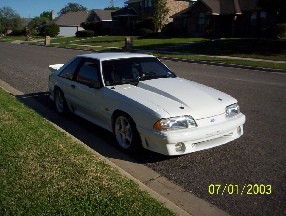 White 1991 Ford Mustang coupe parked on a residential street, viewed from the front three-quarter angle