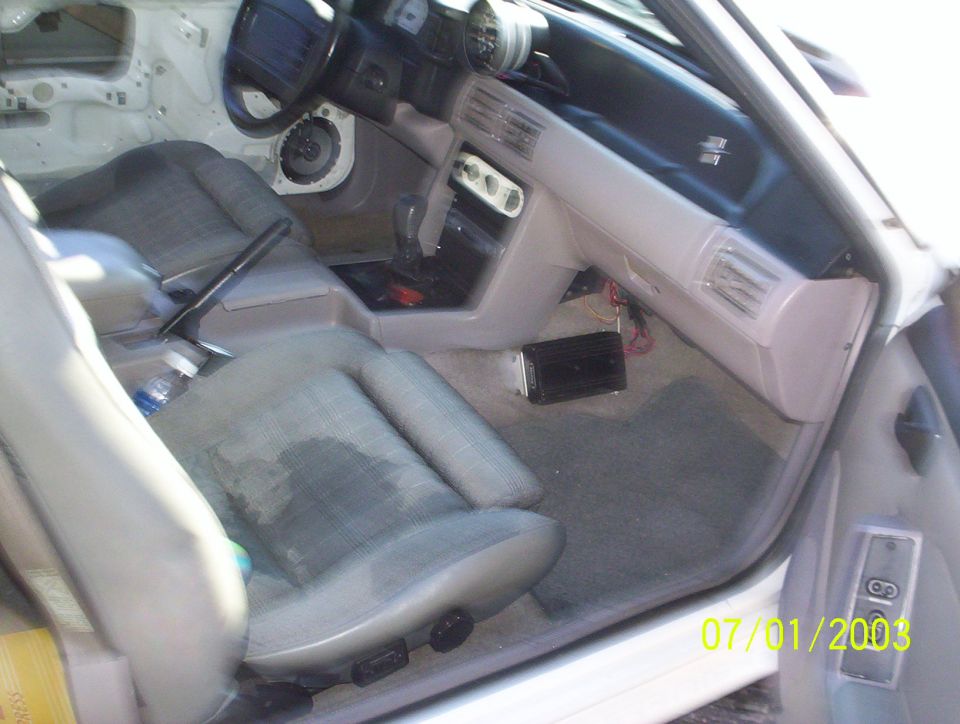 Interior of a 1991 Ford Mustang, showing seats, dashboard, steering wheel, and center console