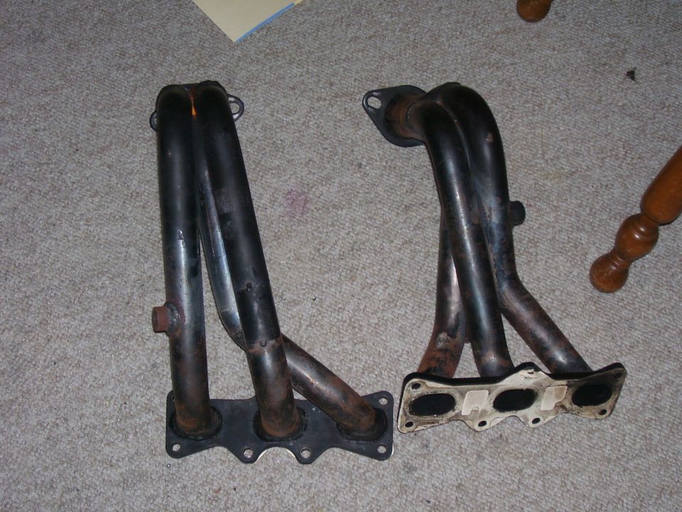 two black exhaust manifolds on a carpeted floor
