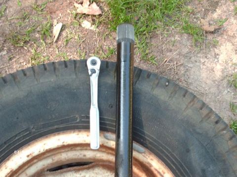 1990 Ford F-150 - An axle shaft and a ratchet are placed on a tire, suggesting a repair or part identification context.