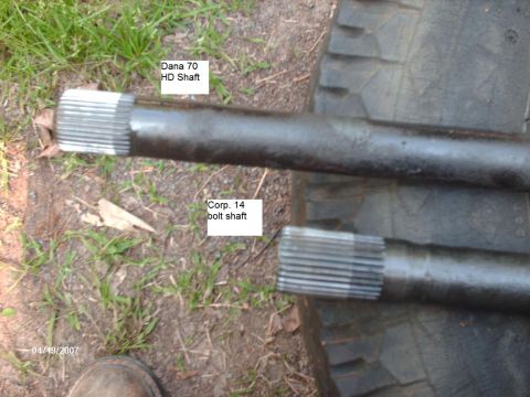 1990 Ford F-150 - Close-up of two different axle shafts, identified by labels, resting on a tire outdoors.
