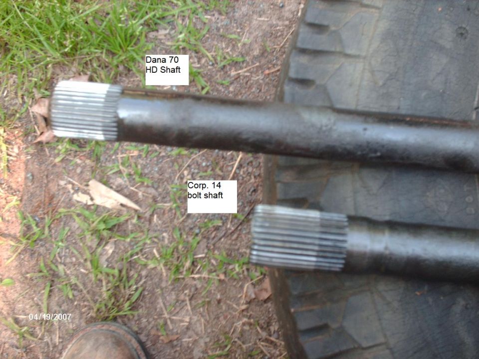 Two axle shafts, labeled Dana 70 HD Shaft and Corp. 14 bolt shaft, lie on a tire