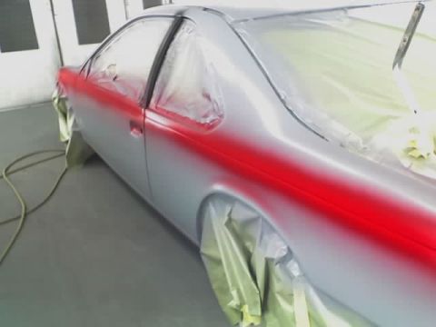 1995 Ford Thunderbird - A car is being painted with a red stripe on its side in a garage.