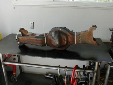 1996 Ford Bronco - A rusty rear axle assembly, likely for a truck or SUV, is displayed on a workbench.