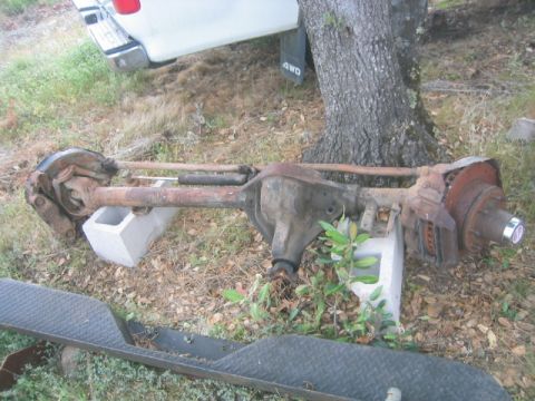 1973 Ford F-100 - A rusty rear axle assembly from a Ford truck is shown outdoors, supported by concrete blocks.