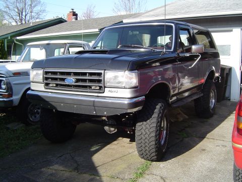 1978 Ford Bronco - This lifted Ford Bronco is parked next to a white pickup truck in a driveway.