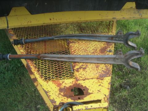 1973 Ford F-100 - Two suspension control arms, likely from a truck, are shown resting on a weathered yellow trailer.