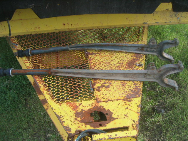 Two used axle shafts with U-joint yokes lying on a rusty yellow trailer deck