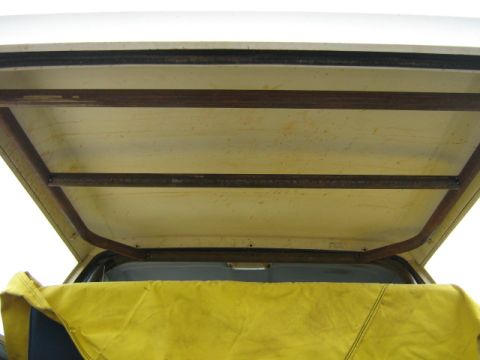 1986 Ford Bronco - The interior of a vehicle shows a metal cage structure above a yellow tarp, with a "Supermotors.net" watermark.