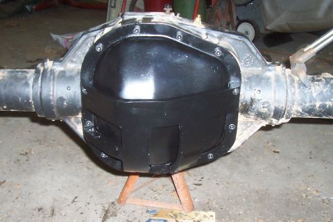 1994 Ford F-150 - A black differential cover is bolted onto a vehicle's rear axle assembly, which is supported by a wooden stand.