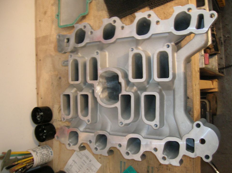 Aluminum intake manifold lower section resting on a wooden workbench