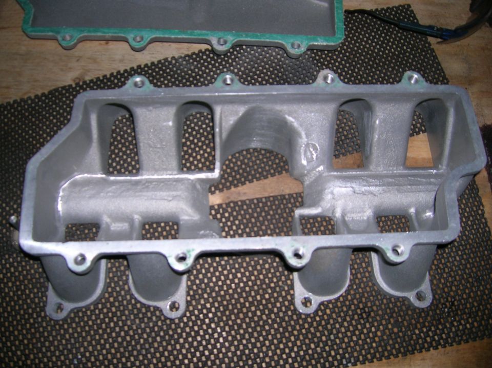 Underside of an aluminum intake manifold on a rubber mat