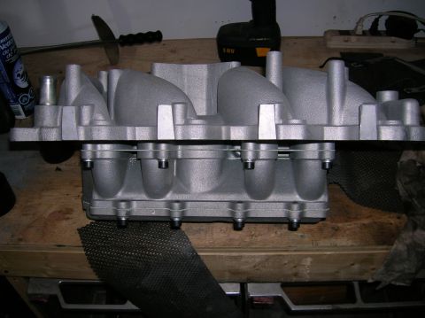 1998 Ford Crown Victoria - freshly finished aluminum intake manifold stands on edge on a workbench, a cordless drill and spray can visible in the background.
