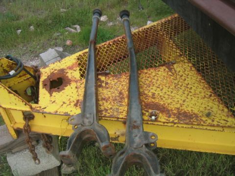 1973 Ford F-100 - Two rusty extended radius arms are displayed on a yellow metal surface with grass in the background.