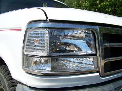 1995 Ford Bronco - Close-up of a white Ford truck's front corner, showing the headlight and grille details.