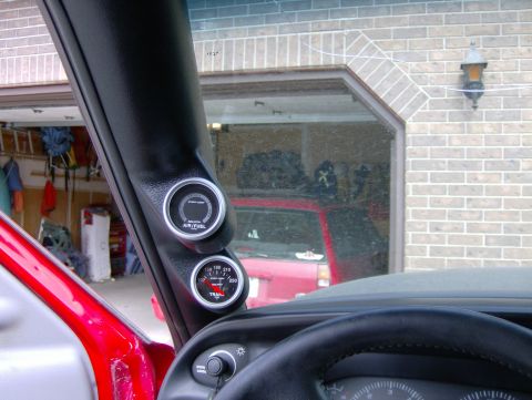 1989 Chevrolet Blazer - Interior view of aftermarket gauges installed in a vehicle, with a red truck visible in the garage behind.